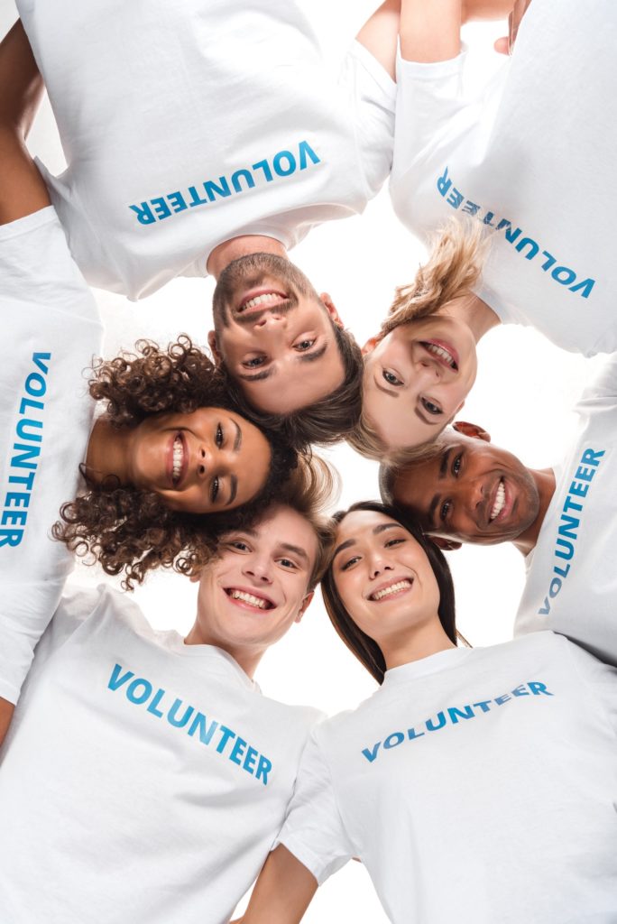 bottom view of multiethnic group of volunteers looking down at camera isolated on white