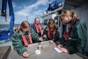Student marine biologists test sea water sample on research ship