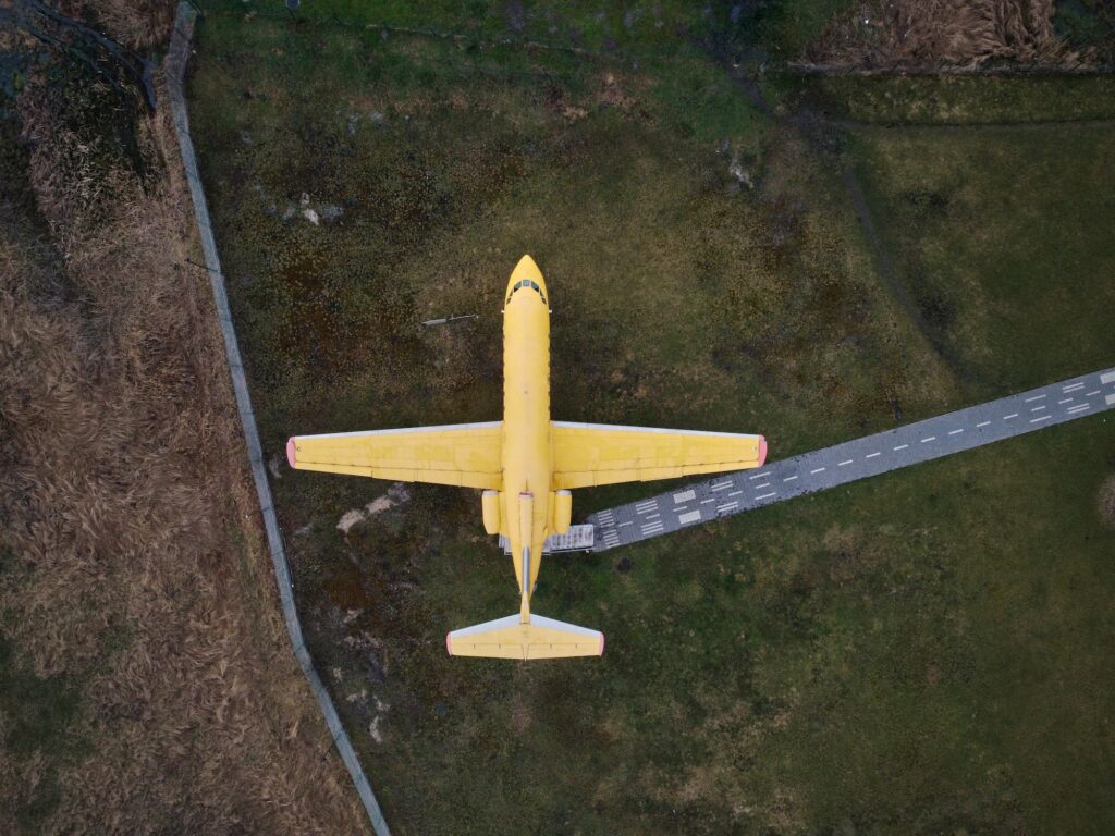 aerial view from drone of a small old jet yellow passenger plane standing in a field
