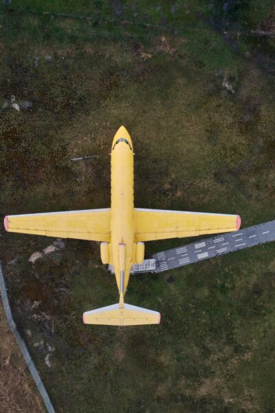 aerial view from drone of a small old jet yellow passenger plane standing in a field