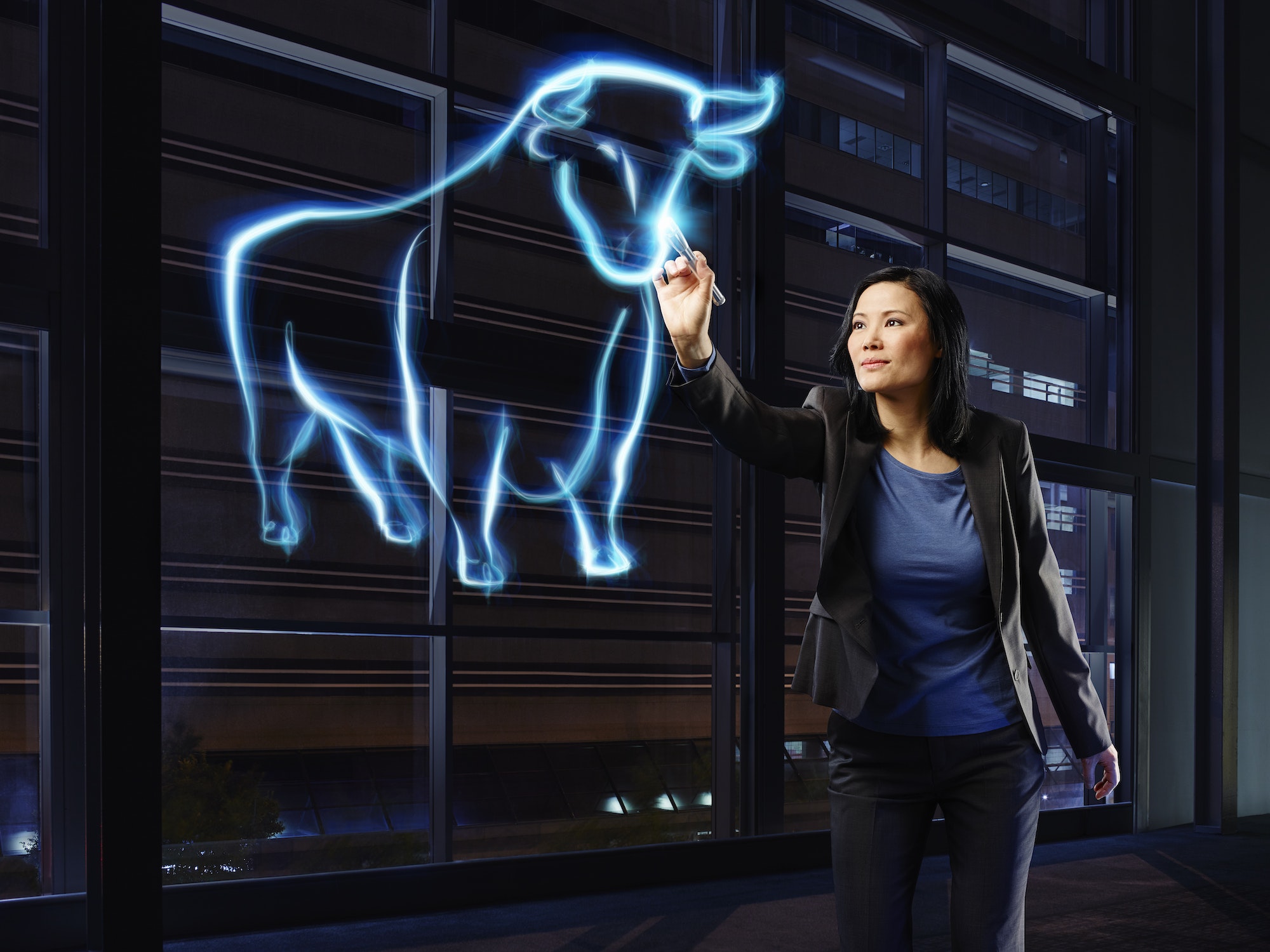 Businesswoman painting a bull with light