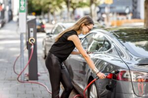 Woman charging electric car outdoors