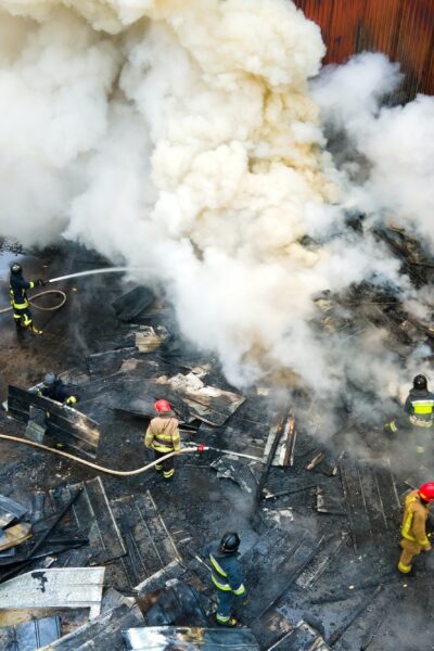 Aerial view of firefighters extinguishing fire in industrial area