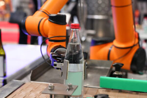 Futuristic automated robotic Hand Picks up a water bottle. Mineral-table water bottling shops.