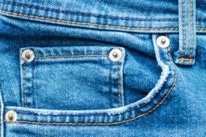 Jeans front with pocket and rivets. Bright blue denim fabric texture background
