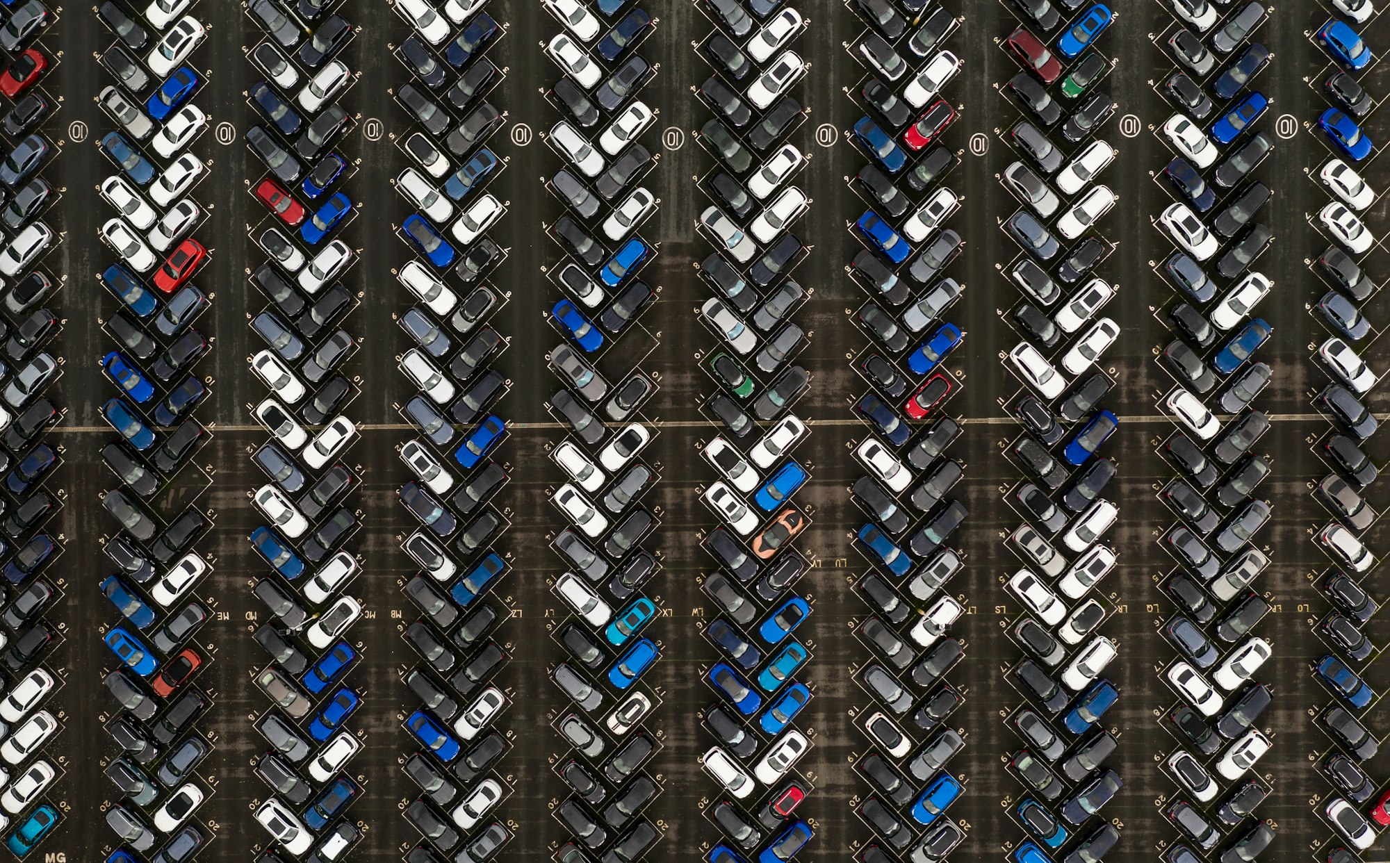Aerial view of rows of new cars in a large park waiting to be shipped for export and import