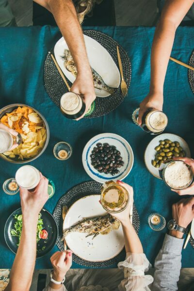 Flat-lay of people eating fish, drinking beer and celebrating together