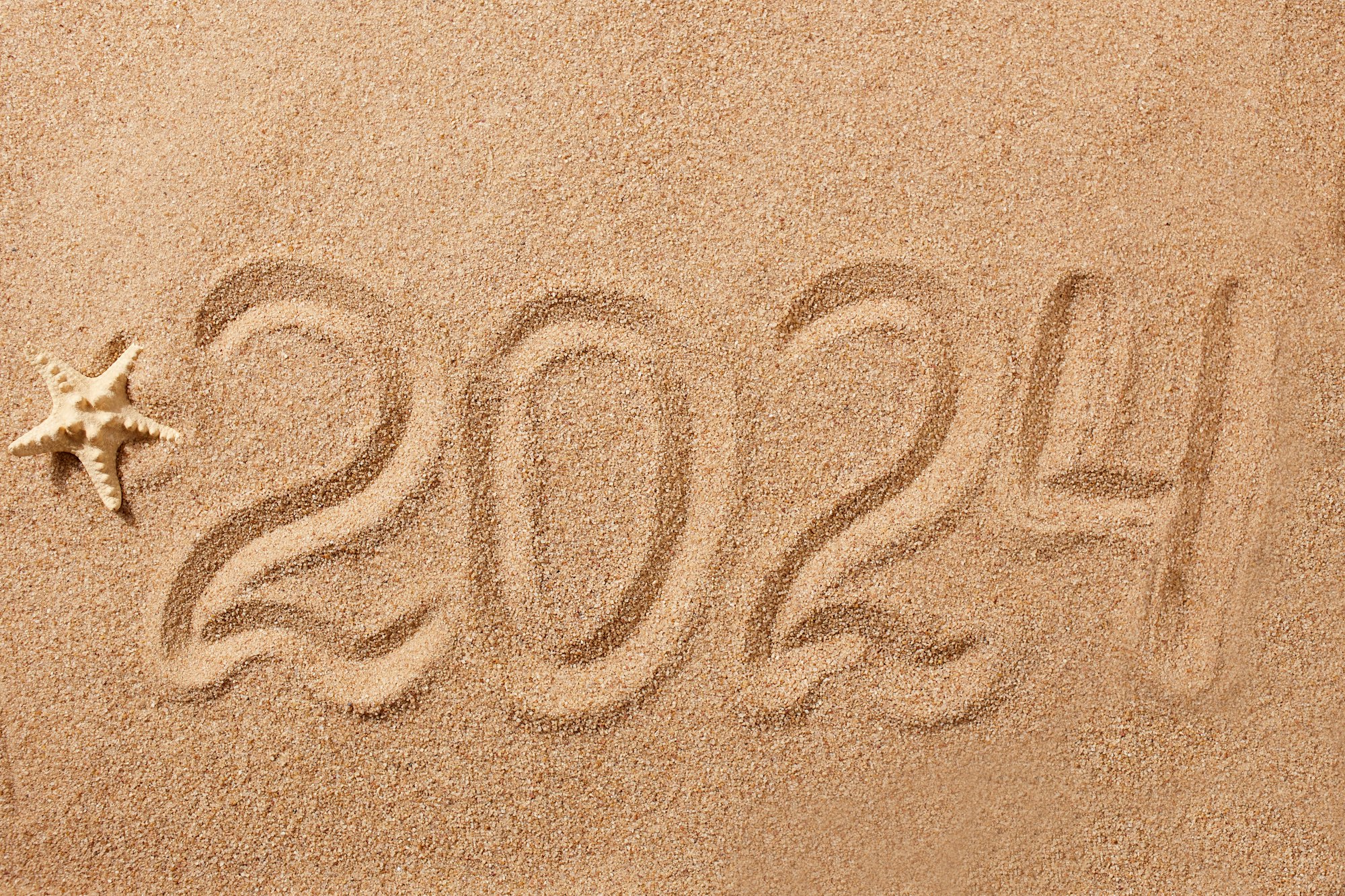 Happy New Year 2024 greeting card. The numbers 2024 on the sand on the beach